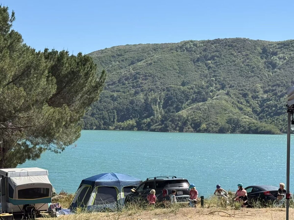 UPNS families and children camping together with tents under shaded trees.