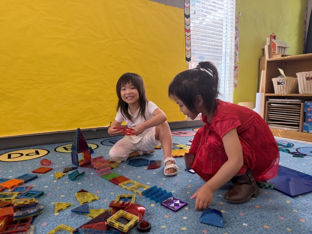 Children building creative magnetic tile towers together on the classroom carpet