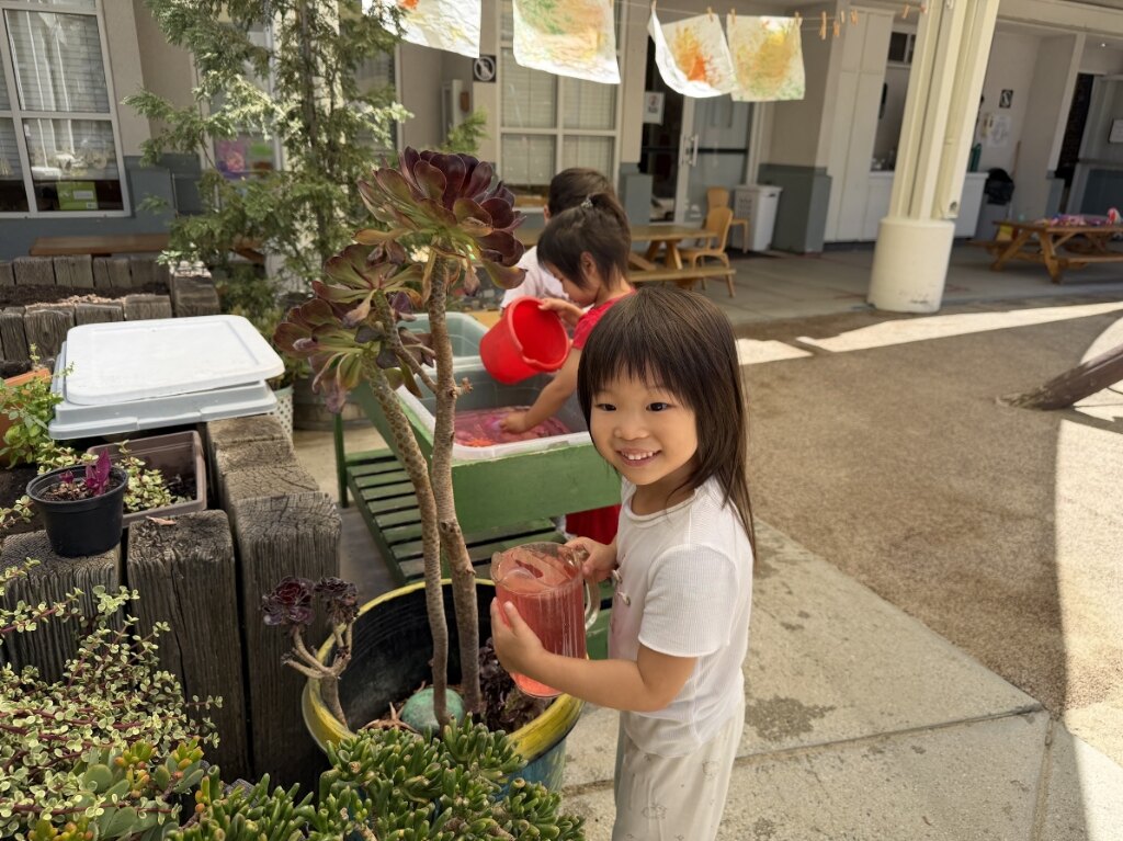 Child exploring gardening and sensory water play in the outdoor yard