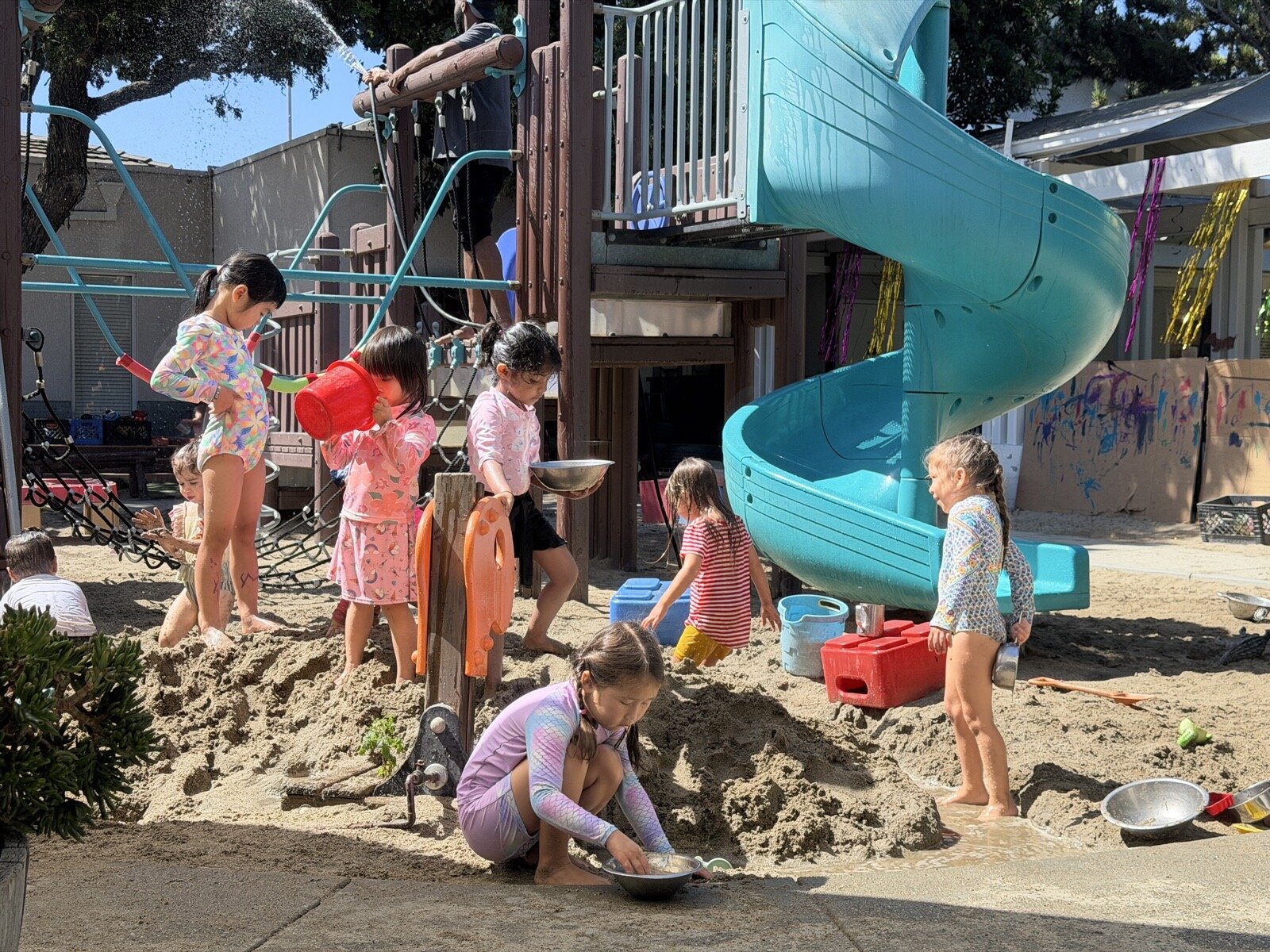 Dolphin Room children exploring the sand pit and playground outdoors