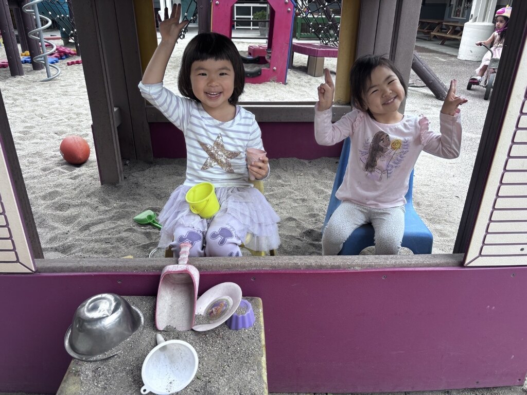 Dolphin Room children smiling and enjoying pretend play in the playground playhouse