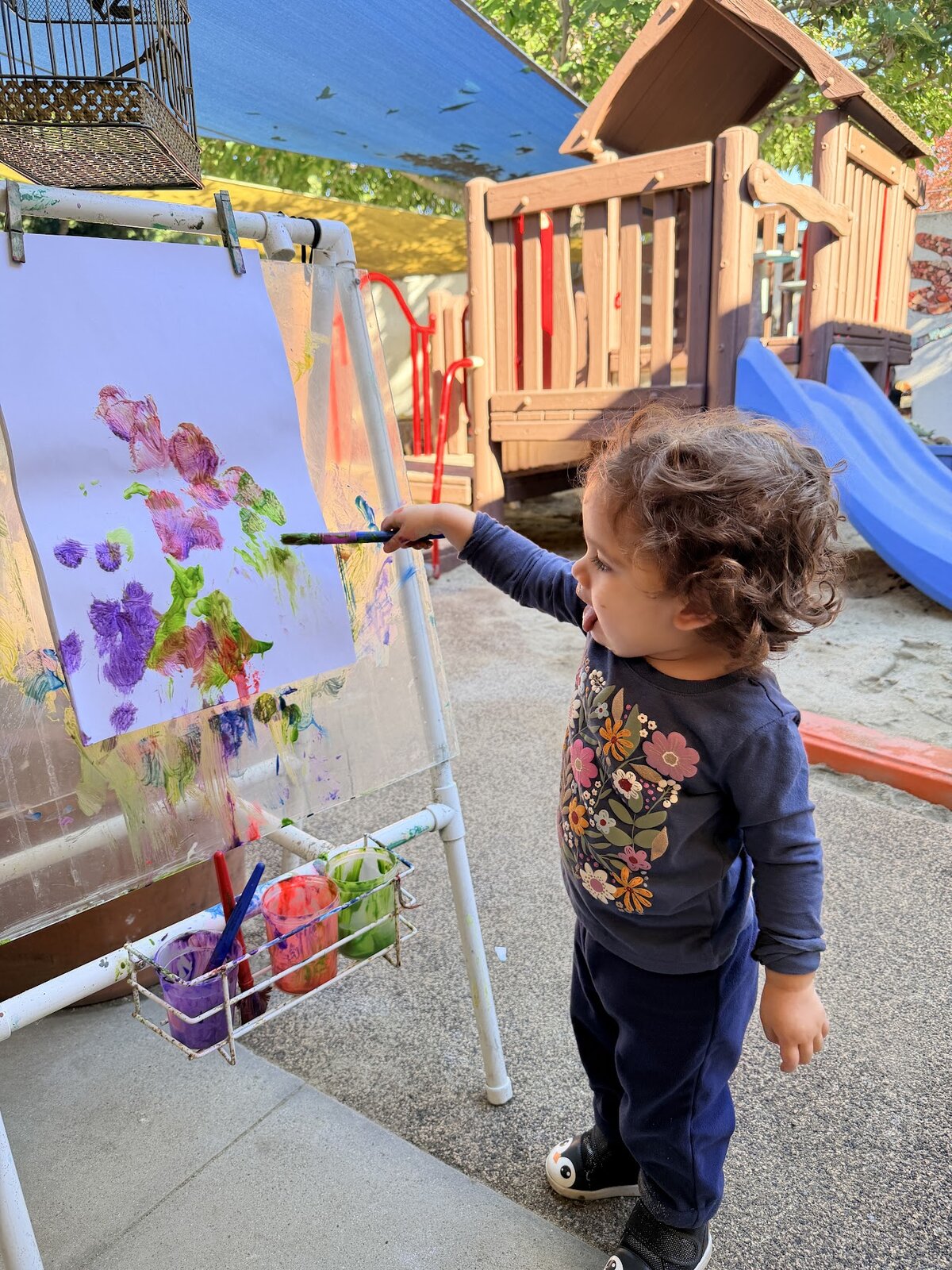 Toddler painting at the outdoor easel in the Kitten Room